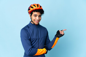 Venezuelan cyclist man isolated on blue background pointing finger to the side - obrazy, fototapety, plakaty