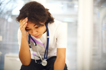 Sad depressed young african american nurse sitting with frustrated face expression - Powered by Adobe