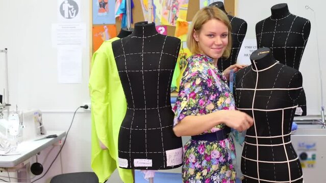 Happy female tailor and five black mannequins in her studio