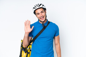 Young caucasian man with thermal backpack isolated on white background saluting with hand with happy expression