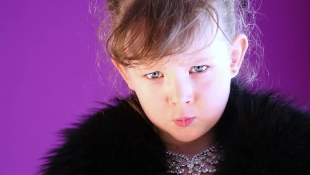 Closeup angry little girl with grey eyes in black fur cape.