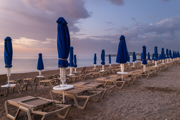 Beach by the sea on the island of Rhodes in Greece. Parasols and sunbeds on the beach. - obrazy, fototapety, plakaty
