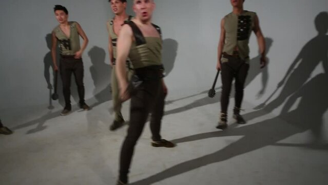 Five handsome guys in medieval costumes attack with maces in studio