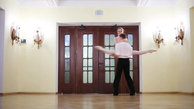 Beautiful couple dancing in a room next to the door