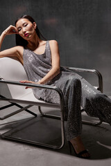 Fashion asian female model in metallic silver glitter suit posing on metallic modern futuristic location.