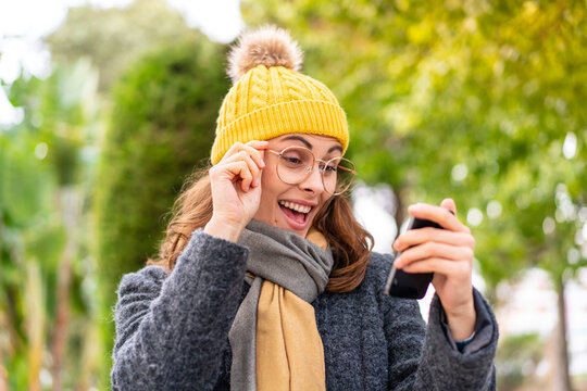 Brunette woman wearing winter jacket at outdoors making a selfie