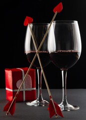 glasses with red wine, gift box and cupid's arrows