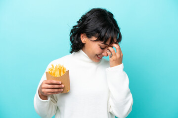 Young Argentinian woman holding fried chips isolated on blue background laughing