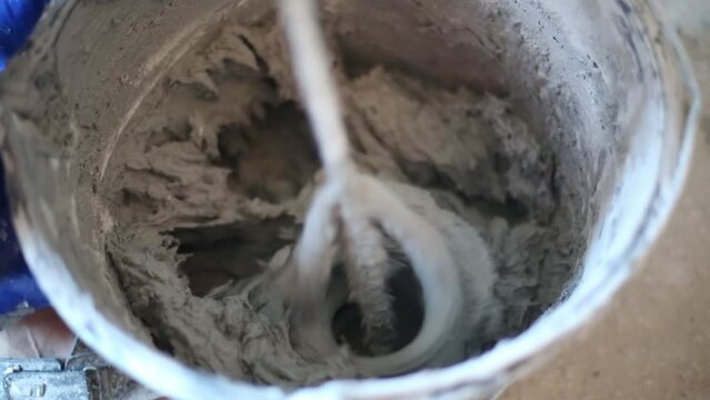 Spinning hand mixer mixing cement mortar for plaster walls