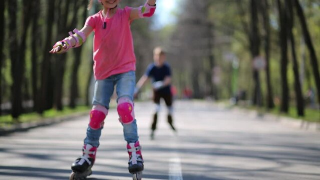 Children ride on roller skates in summer park. 