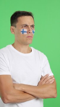 Man with finnish flag painted looking away with serious expression