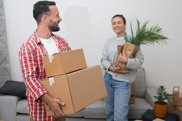 Woman and man filled with joy as carring boxes marking exciting beginning of new apartment...