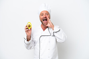 Chef man holding an avocado isolated on white background shouting with mouth wide open