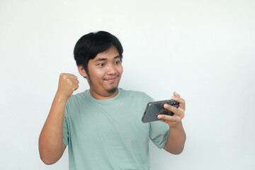 Happy face of Young Asian man in green t-shirt with shocked and surprised when he play on smartphone.
