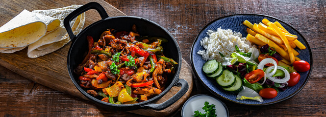Fajita with peppers and onions served on a hot iron skillet - obrazy, fototapety, plakaty