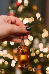 A New Year's glass toy in the shape of a Winnie the Pooh bear in a girl's hand on the background of...