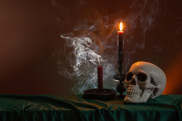 scull and burning candles with halloween decor on dark background