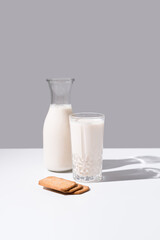 Vaso de leche y botella llena de leche. Desayuno con galletas en un plato sobre fondo gris