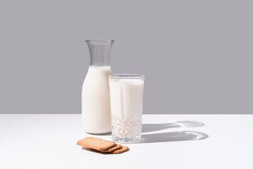 Vaso de leche y botella llena de leche. Desayuno con galletas en un plato sobre fondo gris