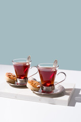 Dos tazas de té rojo con galletas sobre mármol y fondo azul