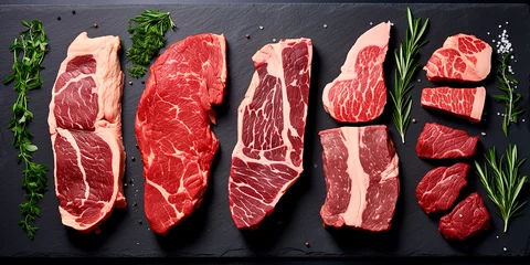 Fotobehang A set of juicy raw steaks and meats with spices and herbs. On a dark background. Flat lay © Татьяна Гончарук