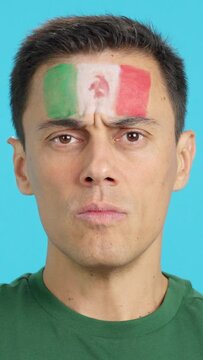 Serious man with a mexican flag painted on the face