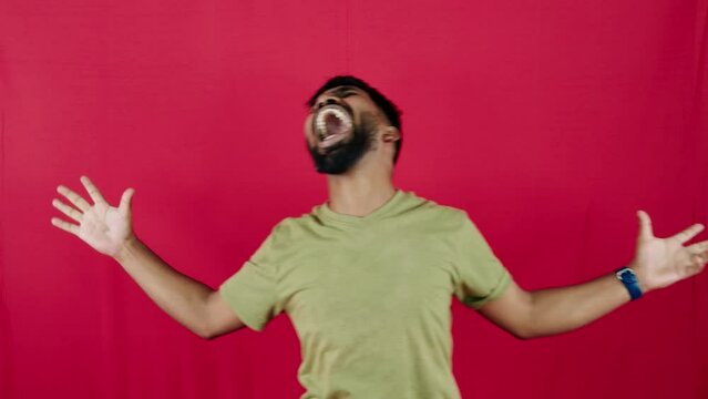 Excited man with arms wide open and shouting yell crazily frustrated against a red background