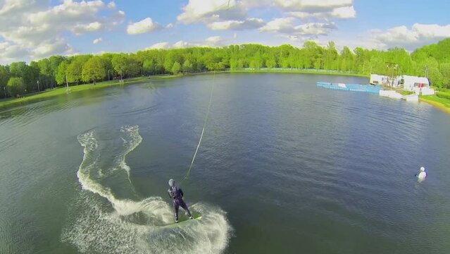 Surfer makes jump stunt during ride by Putyaevskii pond 