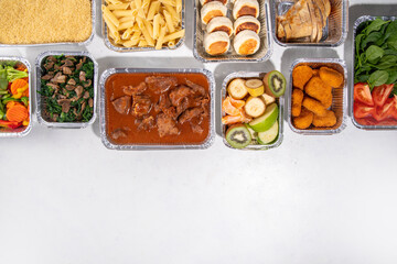 Batch Cooking Meal Prep concept. Several types of side dishes: cereals, pasta, pasta, cooked and fresh vegetables, meat, chicken, nuggets, breakfast pancakes and fruit in food containers 