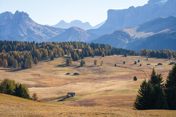 Small cottage in vast and beautiful autumn landscape with mountains and woods, Dolomites, Italy
