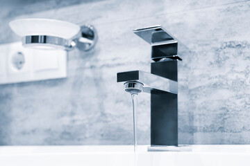 Faucet and white sink in a bathroom interior in blue tone