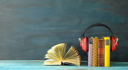 audio book concept, with stack of books, vintage headphones and an open book, good copy space