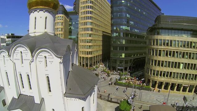People walk near edifice of church and modern office centre