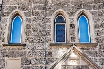 Mittelalterliches Sakralgebäude mit teilweise vergitterten Fenstern und gotischen Sandsteinbögen...