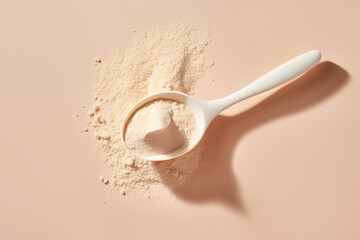 Spoon with BCAA, beta-glucan, anabolic whey protein powder or nutrition yeast. Isolated beige color background. Top view. Minimal flat lay. Concept of food or dietary supplements.