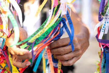 Catholics are seen tying ribbons on the railing of the Senhor do Bonfim church during an open mass...