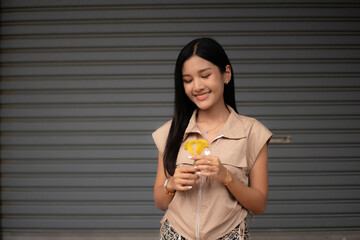 A young woman dressed in vintage clothes holds a yellow flower and admires it in her hand.