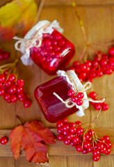 viburnum jam. Red juicy berries of a viburnum with sugar in a glass jar on a dark wooden background. For making jam, tea. Medicinal plant.