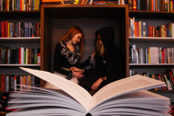 Two lovers, a guy and a girl, are sitting in the library among the bookshelves on Valentine’s Day...