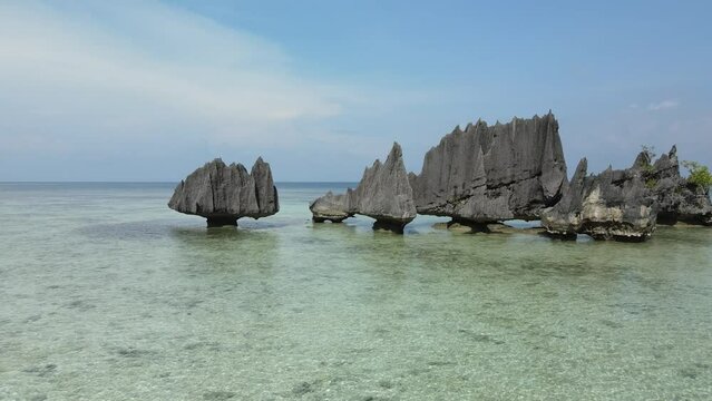aerial shoot, flight over colourful lagoon with Turquoise water, sand beach and palm trees in Raja Ampat Indonesia