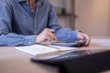 Closeup of young asian student women use calculator to learning knowledge remote education from home and taking notes in notebook while studying and watching lecture webinar in online class on tablet