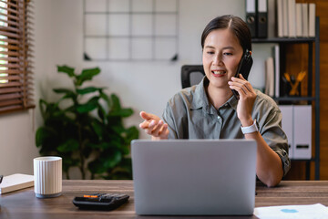 Casual business women reading financial data on laptop and talking with colleague on smartphone
