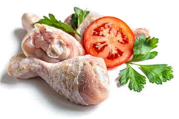 fresh raw chicken legs seasoned with spices, parsley and tomatoes isolated on white