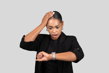 Shocked African American businesswoman looking at her watch realizing the urgency of time