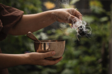 hand with singing bowl in india holds white sage for energetic cleansing 