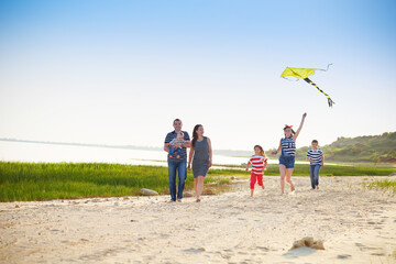 Happy young family with flying a kite on the beach