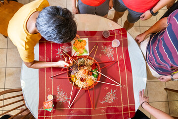 Person placing raw salmon belly onto a serving of yusheng or yee sang during Chinese New Year,...