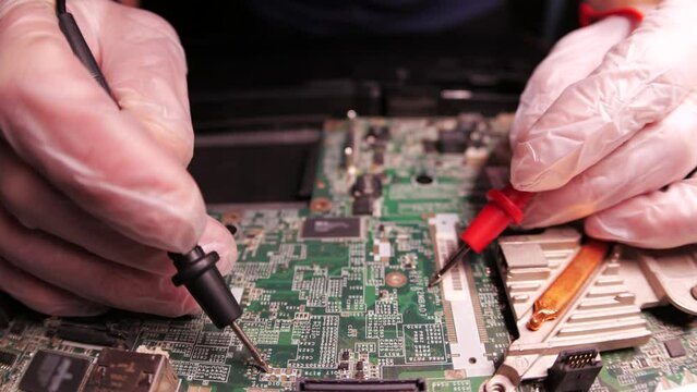 The master fixes notebook motherboard, using tools. Close up hands, black table, diy