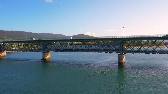 Aerial shot of cars and a train passing over a river in a bridge.
