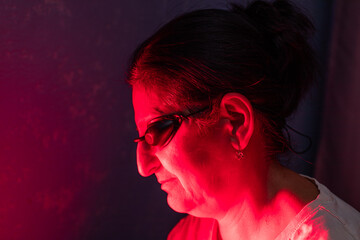 Closeup of Senior Woman face doing the Red Light Therapy Session with Panel